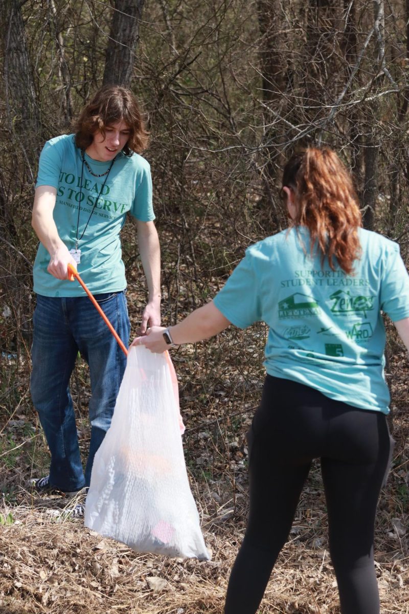 Two students clean up trash as part of the day of service
